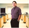 Dr. Andy Watson smiling in a portrait shot with a student lab in the background