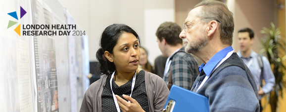 A participant and a judge at London Health Research Day in front of a poster.