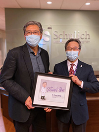 Dr. John Yoo presents Dr. Davy Cheng with a framed illustration