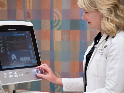 Dr. Karen Bosma selecting a mode on a ventilation machine