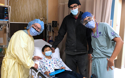 Faculty members posing with a paediatric patient and his father