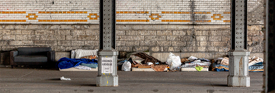 area for homeless individuals with personal belongings scattered on the pavement under a bridge