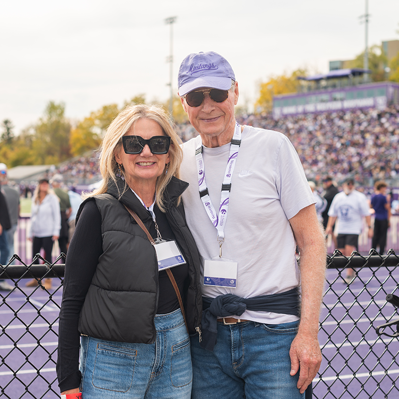 Western alumni and supporters watching a football game from the sidelines during homecoming weekend.