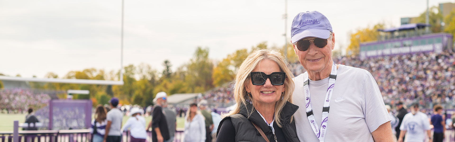 Western alumni and supporters watching a football game from the sidelines during homecoming weekend.