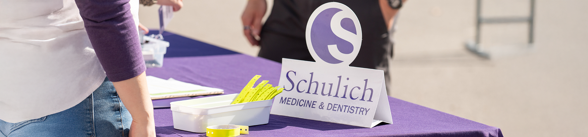 Schulich Medicine & Dentistry welcome table with event registration materials and wristbands.