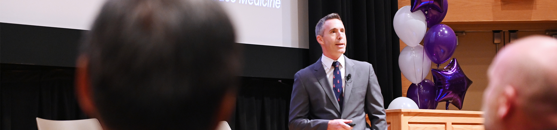 peaker presenting at a Schulich Medicine & Dentistry alumni event with audience in attendance.