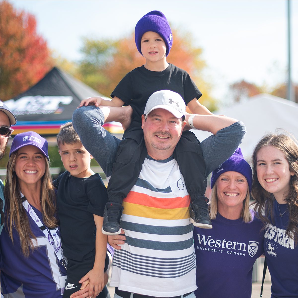 Family and alumni celebrating at a Western homecoming event outdoors.