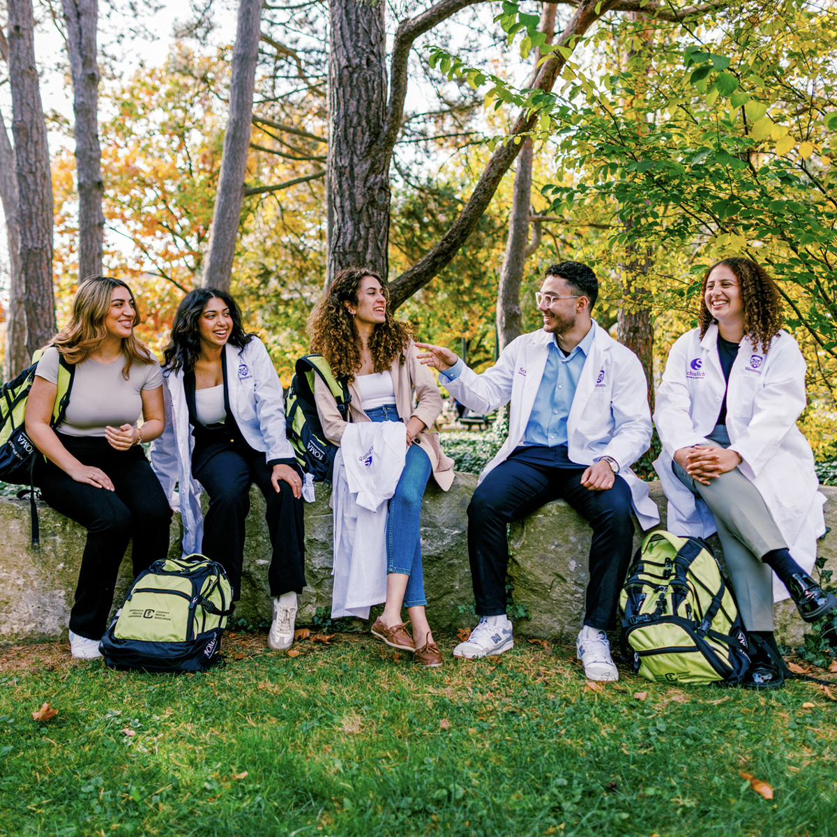 Group of students sitting outdoors on campus near trees