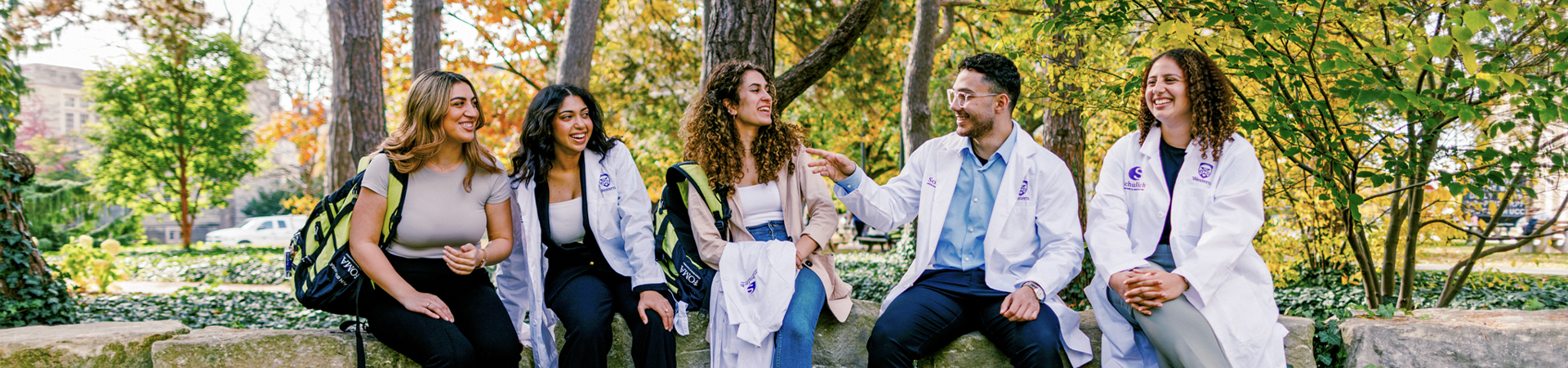 Group of students sitting outdoors on campus near trees