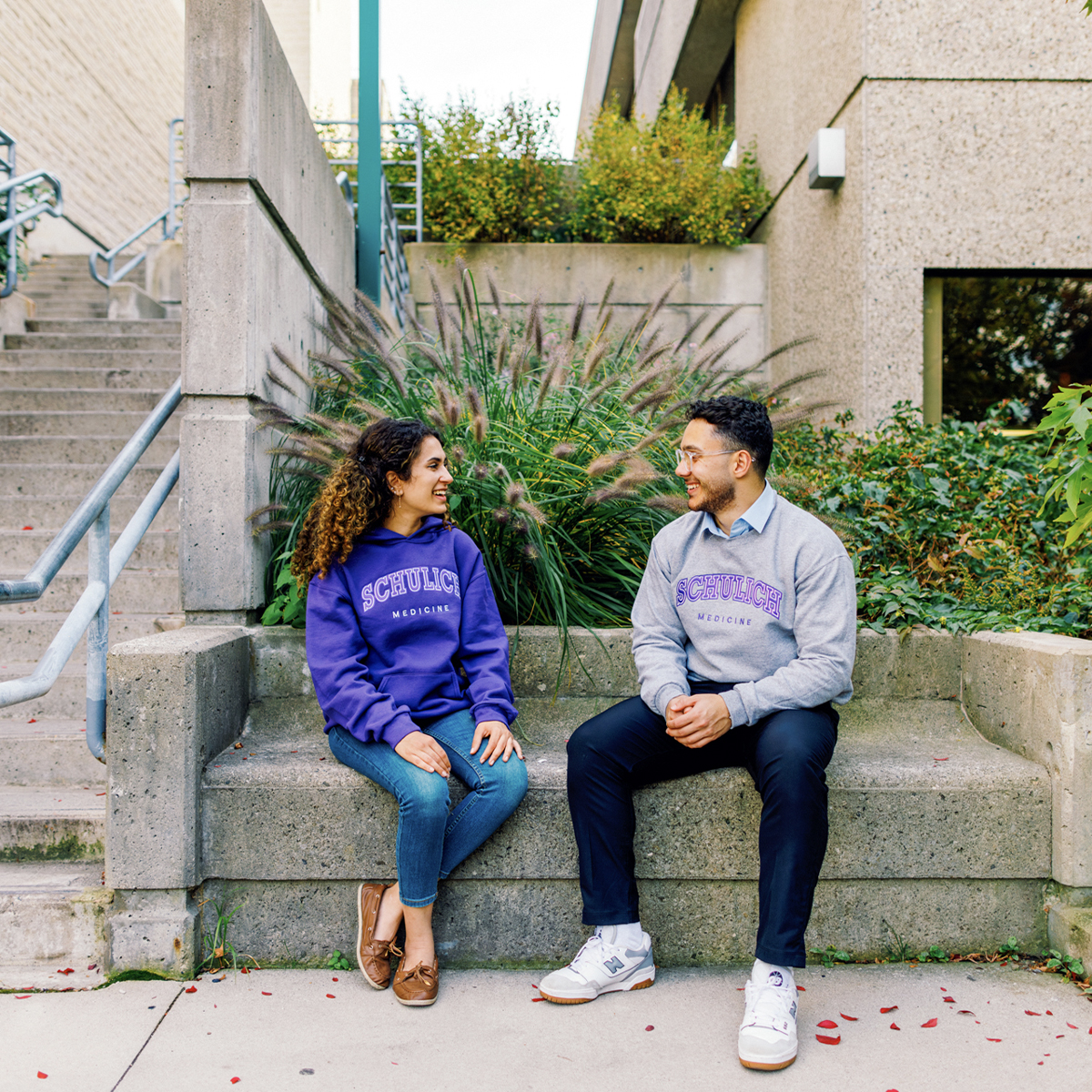 Two students sitting and talking outdoors near a building