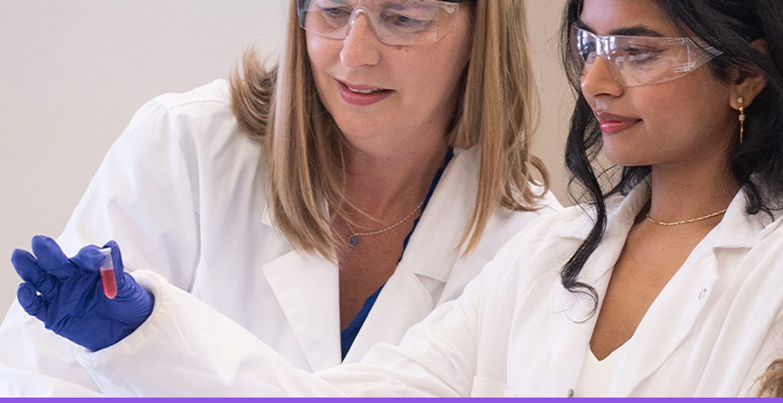 Instructor showing student a vial in a lab