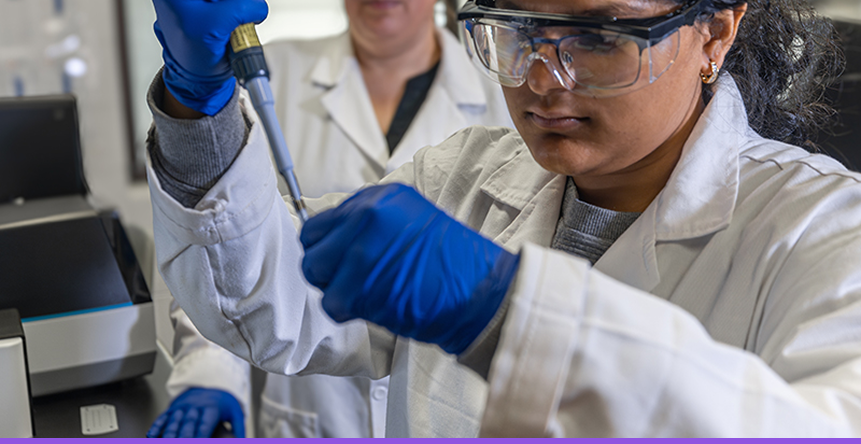 Student in lab coat using pipette in a science lab