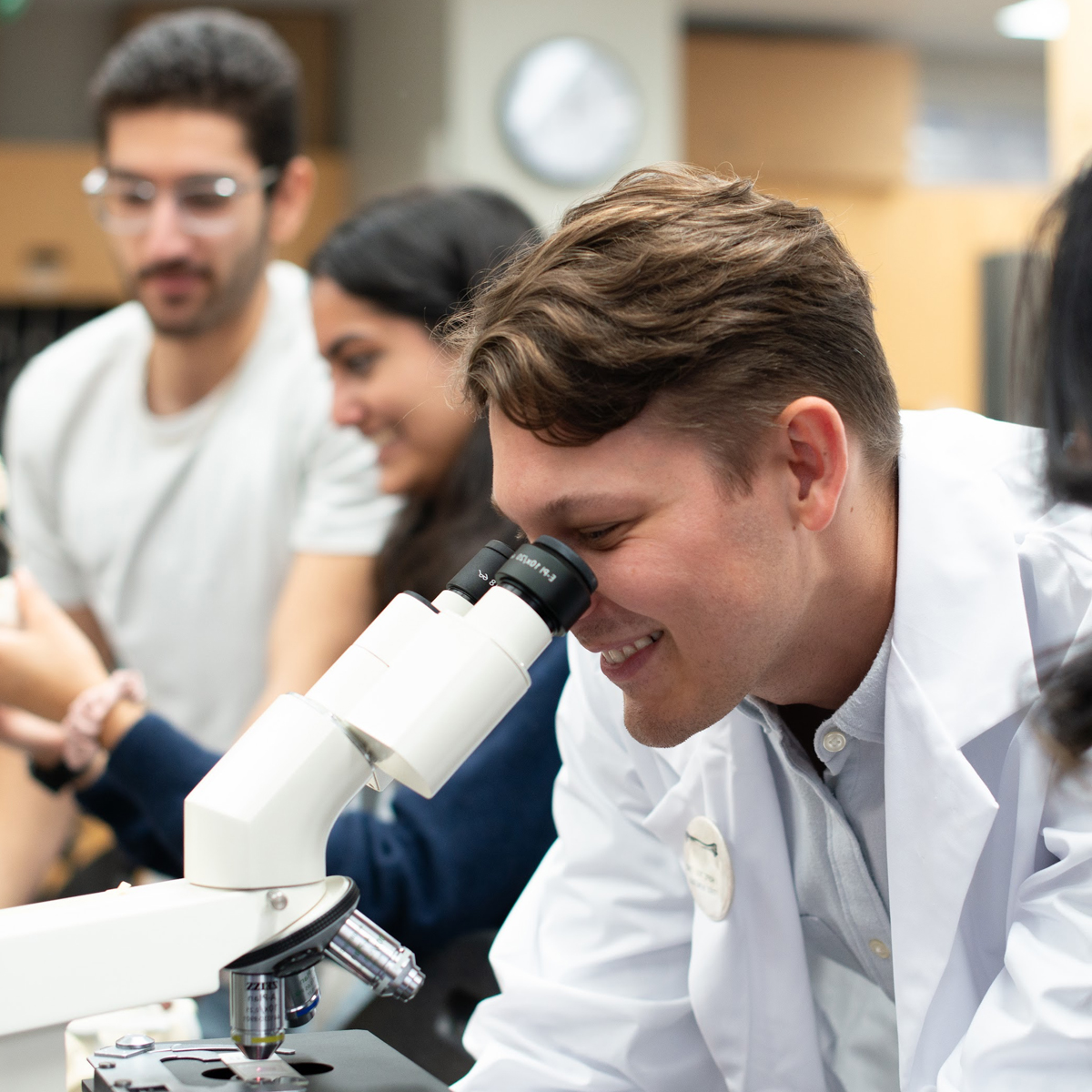 Students in a lab, one using a microscope.