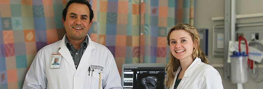 white male and female learners wearing white coats, standing infront of an ultrasound machine