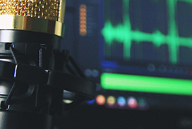 microphone and computer in the background displaying green sound waves