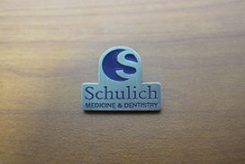 Metal lapel pin with purple Schulich Medicine & Dentistry logo
