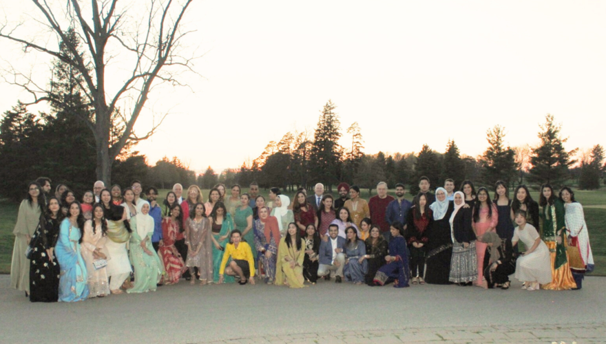 Group photo of Eid Party attendees against backdrop of setting sun