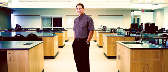 Andrew Watson smiling for the camera in an empty lab.