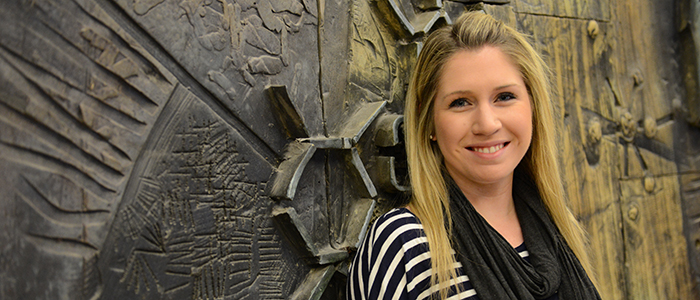 Morgan Black smiling for the camera in front of a wall.