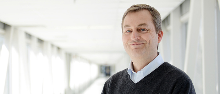 Rodney Dekoter smiles for the camera with a bright background.