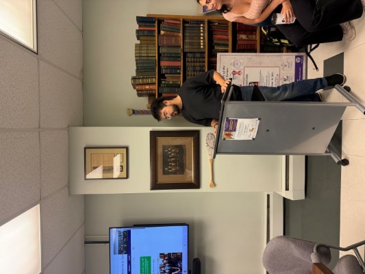 A person standing at a lecturn in front of an audience