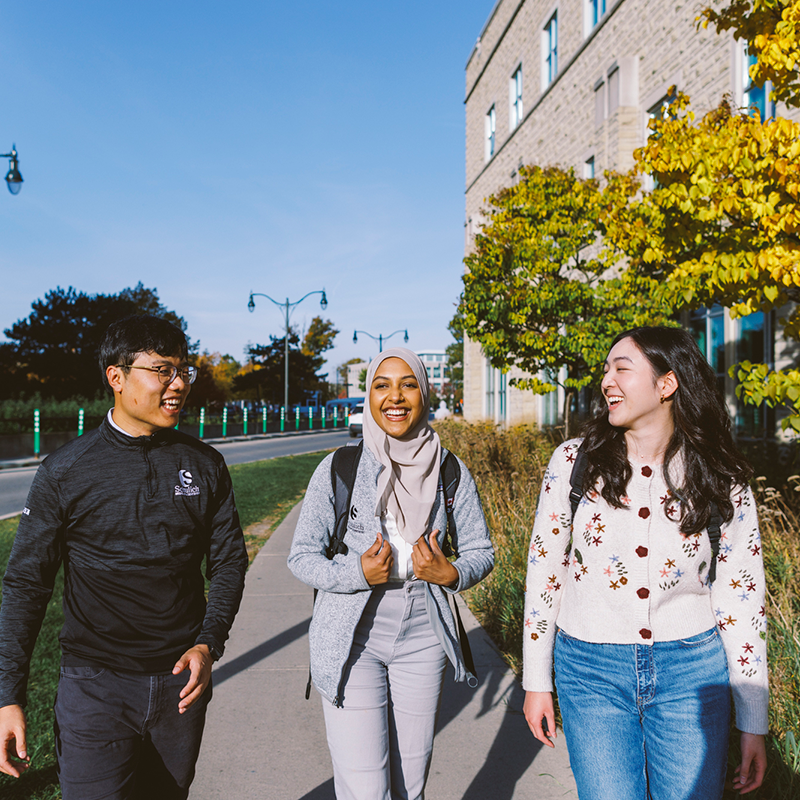 Three Schulich students walking on campus and chatting.