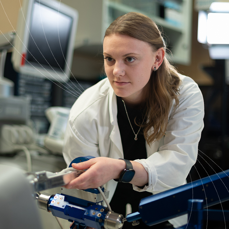 Researcher in a lab coat adjusting equipment in a laboratory.