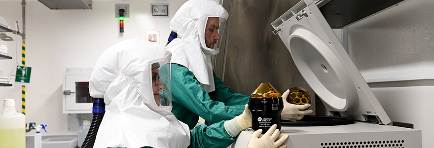 In head-to-toe PPE, two postdoctoral fellows work side-by-side inside the biocontainment lab