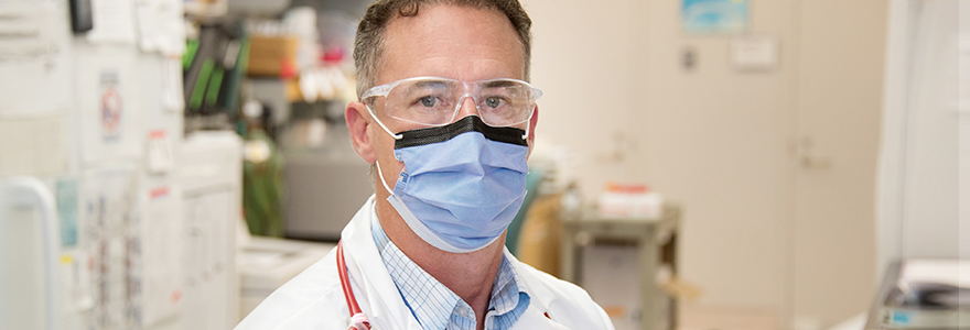 Douglas Fraser with a mask and safety glasses in a lab setting