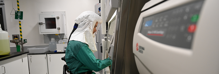 Researcher wearing full body PPE working inside ImPaKT biocontainment facility