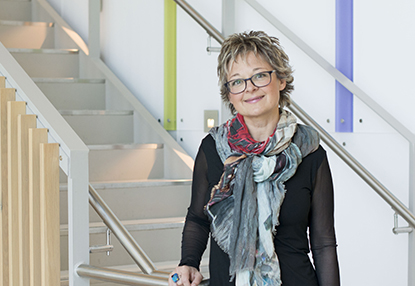 Photo of Janet Martin standing by a staircase looking at the window