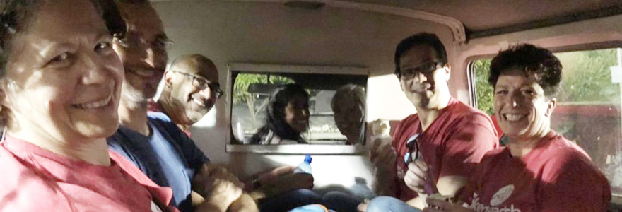 A team of smiling doctors take a selfie in a cramped vehicle