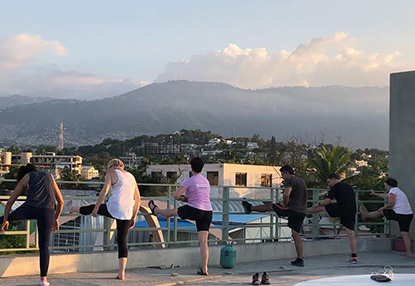 Doctors and nurses stretch their legs on the roof of the hospital with a rolling hillside and sunset in the background