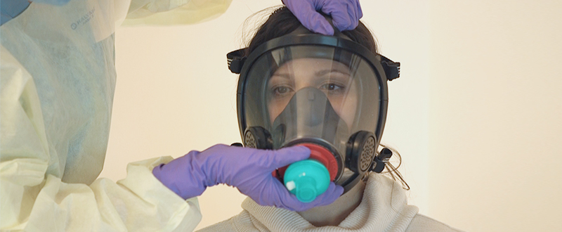 Image of gloved hands placing the modified fighfighter's mask over a person's entire face