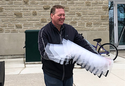 Engineering faculty member delivers a stack of faceshields