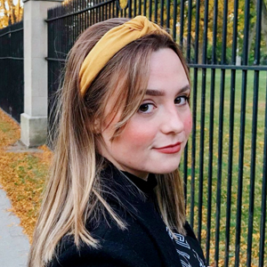 Madison Curtis posing outside by a wrought iron fence