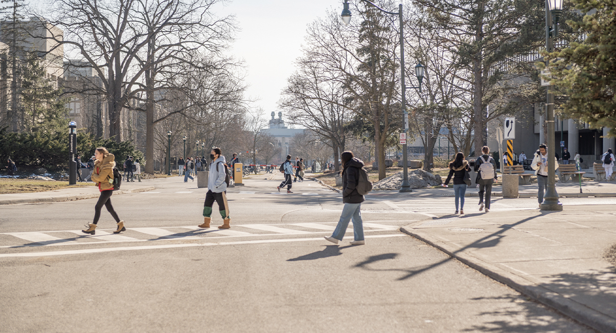Students crossing a campus roadway on a sunny day