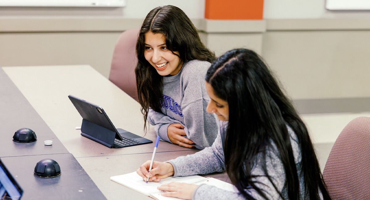 Two students studying together and writing notes