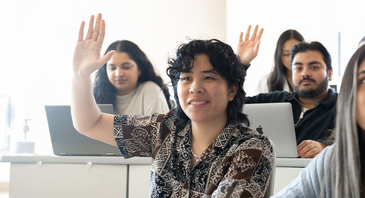 Student raising a hand in a lecture hall