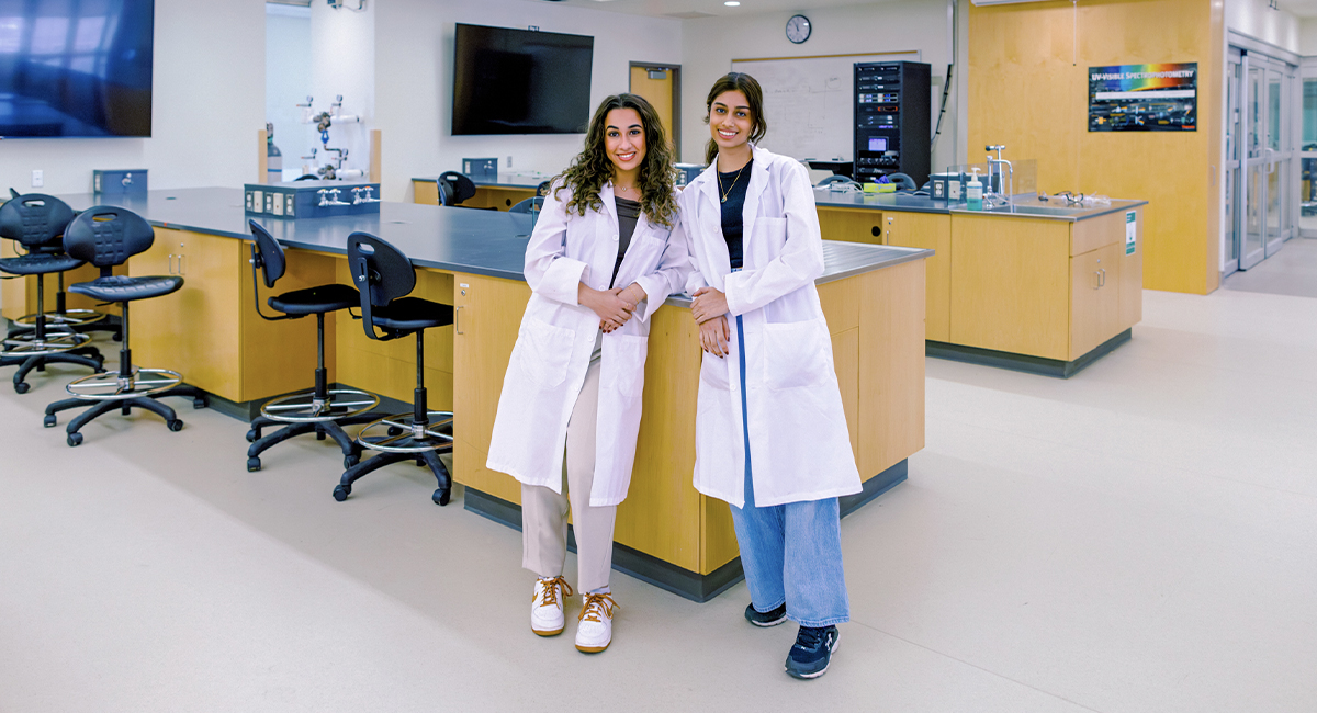 Two students in lab coats standing in a biomedical lab