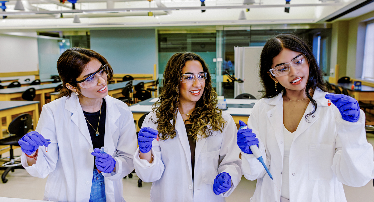 Students in lab coats holding pipettes in a teaching lab