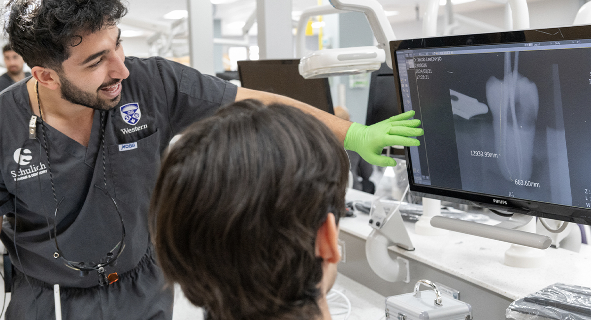 Clinician reviewing dental x-rays on a monitor with a student