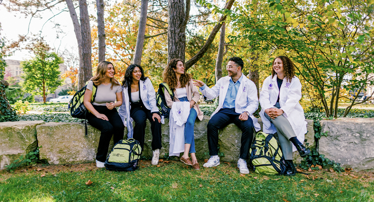 Group of students sitting outdoors on campus near trees