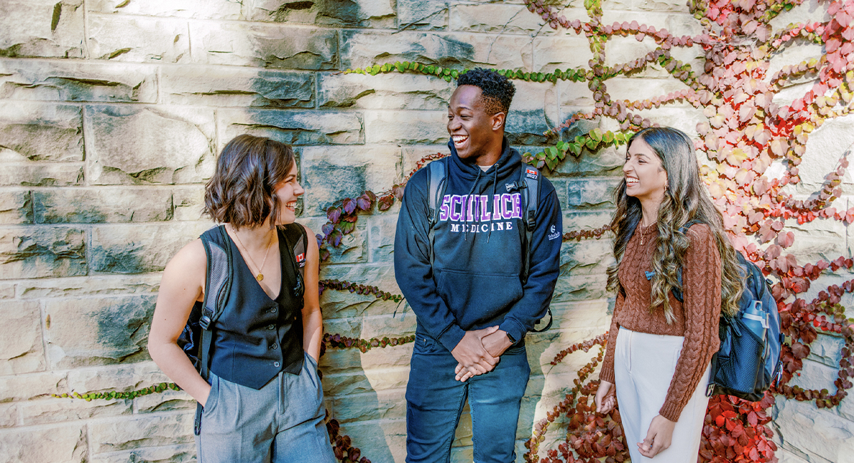 Students talking outside a campus building with an ivy-covered wall