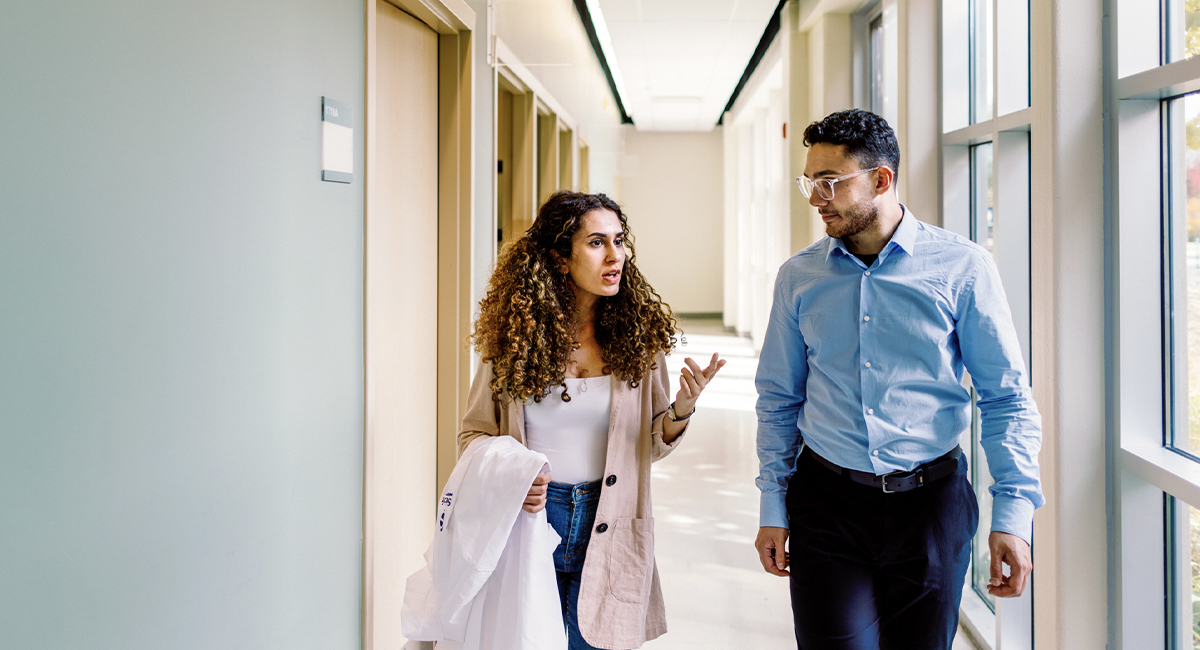 Two people walking and talking in a campus hallway