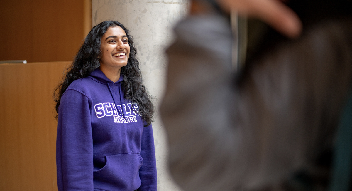 Student wearing a Schulich hoodie smiling indoors