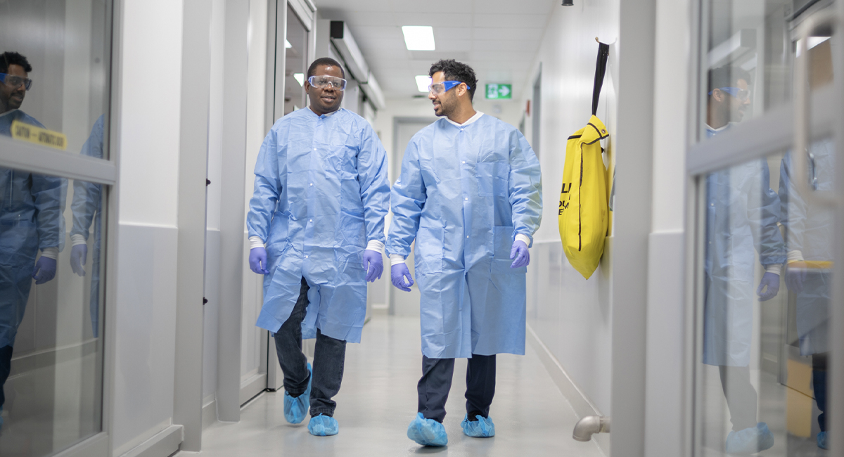 Researchers in protective gowns walking through a lab corridor