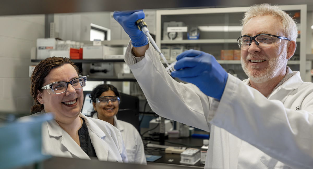 Research team in lab coats using pipettes in a laboratory
