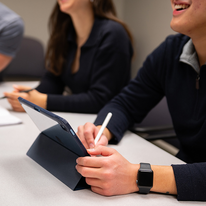 Medical students taking notes on a tablet