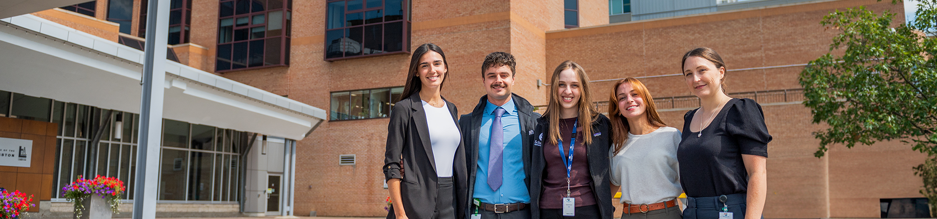 A group shot of five clinicians outside the glass building